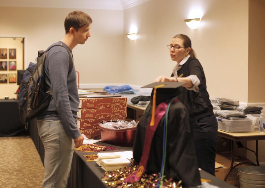 Biology senior Christian Casto talks with assistant manager Rajean Schulze about buying a cap and gown at Imagine Graduation in Commanche on March 12. Photo by Brittni Vilandre 
