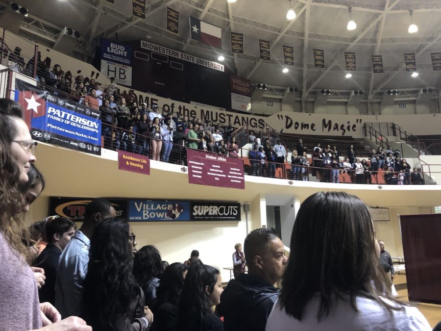 Prospective students and guests standing in bleachers.