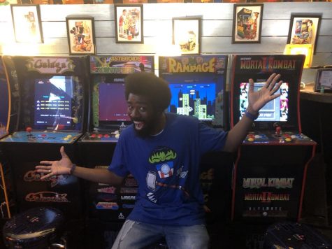 Man sits on bar stool in front of four traditional arcade games