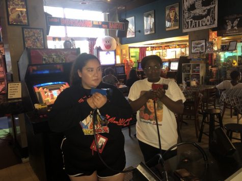 Two students hold toy guns while playing two-person shooter arcade game