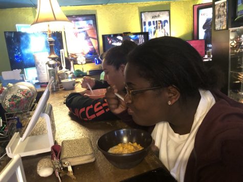 Two students sit at bar eating cereal