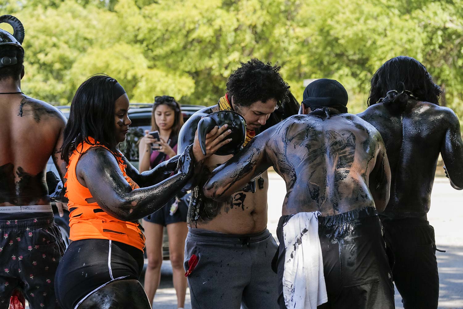 Parade members cover each other in oil as part of tradition.
