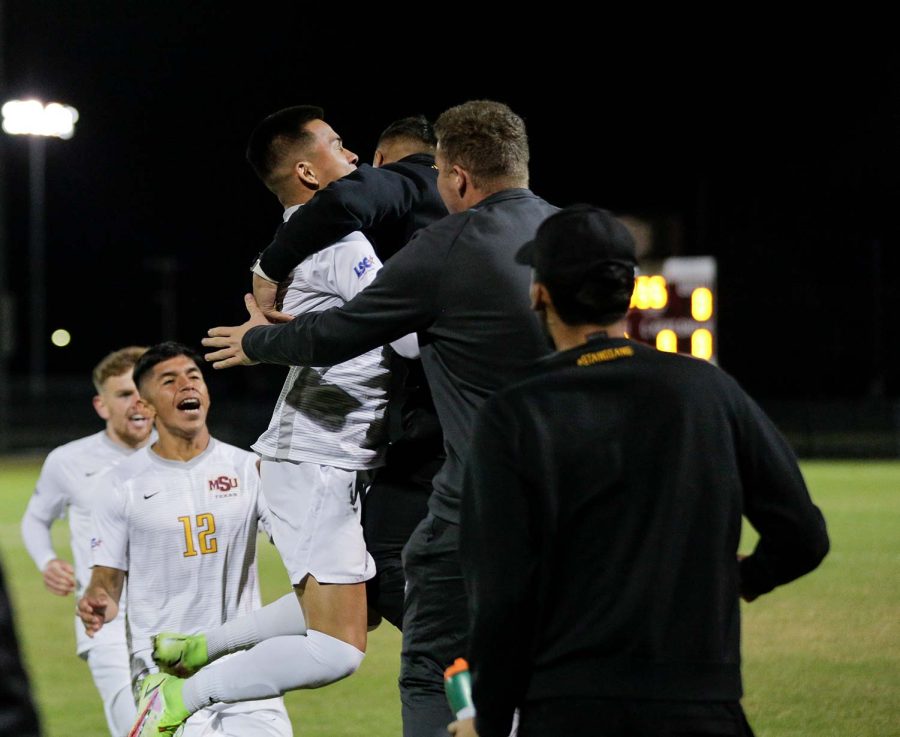 Business management sophomore and forward Mere Escobar jumps and hugs his teammates after scoring the first goal of the game against St. Mary's.