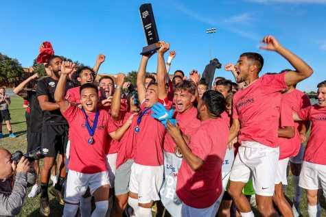 Kinesiology senior and midfielder Carlos Flores holds up the Stangs trophy as he and his team celebrate their victory against Lubbock Christian University which made them champions of the regular season and Lone Star Conference Postseason Tournament.
