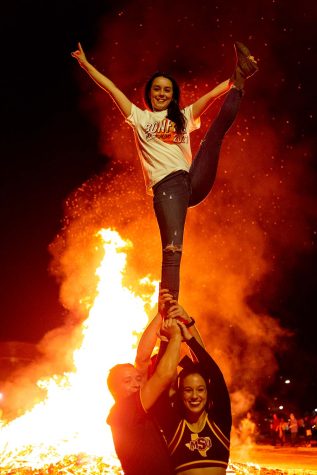 Accounting senior Kassidy Knight is held up by cheerleaders kinesiology senior DanLee Duncan, mechanical engineering junior Robert Hollingsworth and nursing senior Ashleigh Miller as they all stand in front of the bonfire, Oct. 29.
