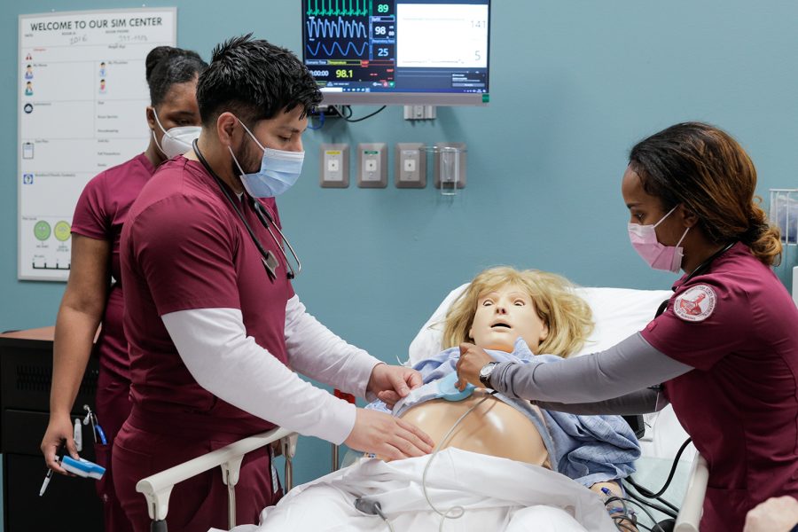 Nursing seniors Christian Trejo and Fasika Kifle strap a fetal heart monitor onto a pregnant simulation dummy, Mar. 10.