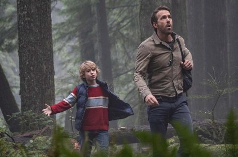 Young Adam Reed, played by Walker Scobell, and older Adam, played by Ryan Reynolds, walk through the woods.