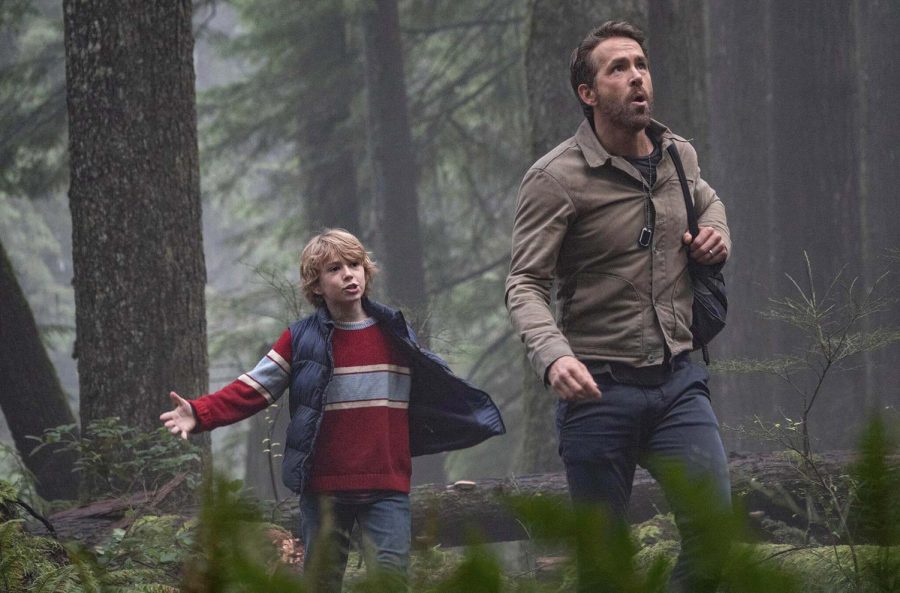 Young Adam Reed, played by Walker Scobell, and older Adam, played by Ryan Reynolds, walk through the woods.