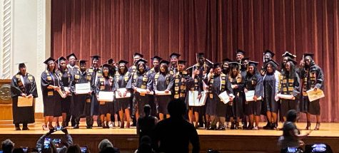 Black graduates stand together on the stage at the end of the ceremony, 2022.