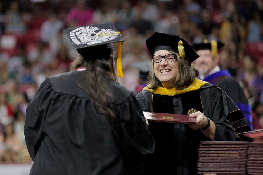Dean of McCoy College Marcy Brown Marsden hands a degree to a graduate of her college.