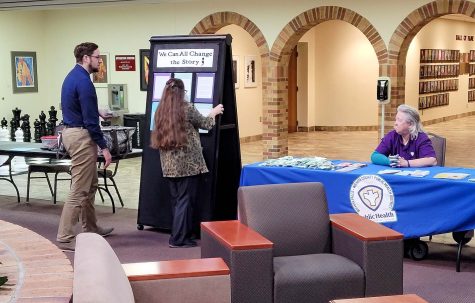 Counseling Center assistant director Zachary Zoet and medical office coordinator Christina Gragg set up the Share Your Story exhibit while Karel Davis of the Wichita County Health Department watches, Sept. 22.