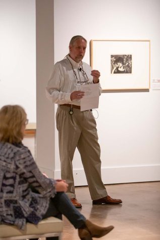 While standing in front of "Faces in the Crowd" by Mable Dwight, Giles reads the poem "Spring and All" by William Carlos Williams to open the exhibit, Oct. 20.