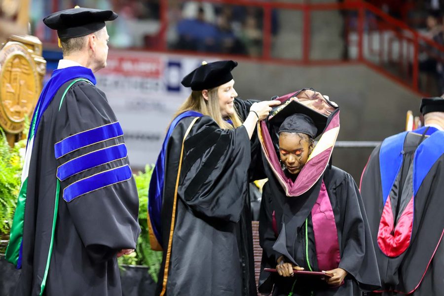 A student has their hood placed to designate their achievement of a masters degree, May 13.