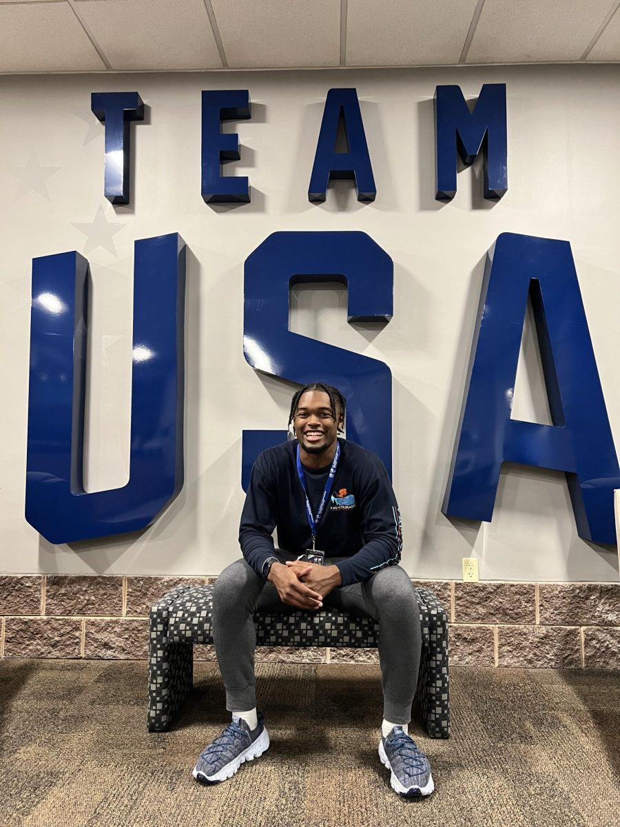 Kinesiology graduate Jace Johnson sits in front of a Team USA logo, 2023. Johnson is one of 38 on the team, and is waiting to find out which crew he will run with. 