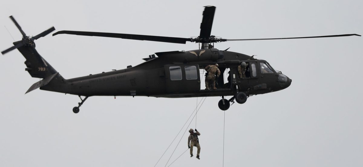 Airmen rappel out of a helicopter during the air show, landing on the airstrip, April 27.