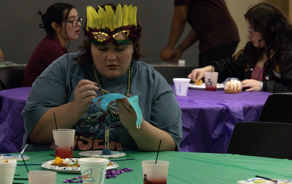 Hazel Harris, radiology freshman, paints a Mardi Gras mask for the celebration, March 1.