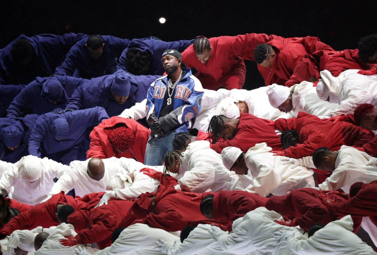 Kendrick Lamar stands in the middle of dancers dressed to resemble the American flag